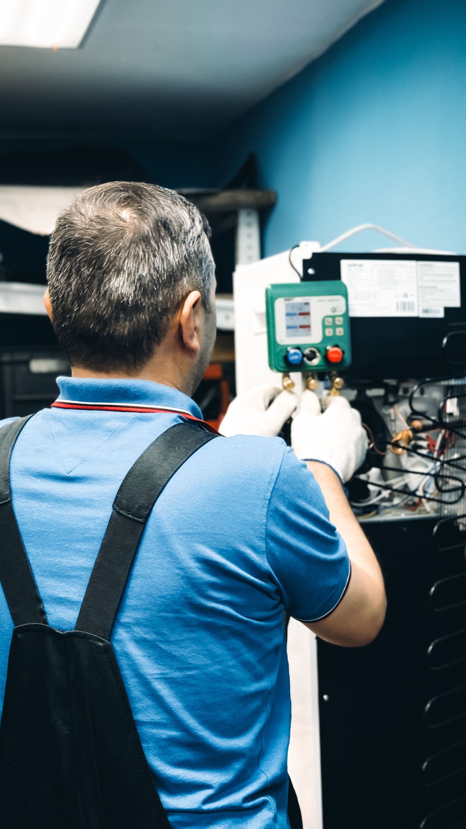 Air-conditioning technician testing cooling equipment with digital service gauges