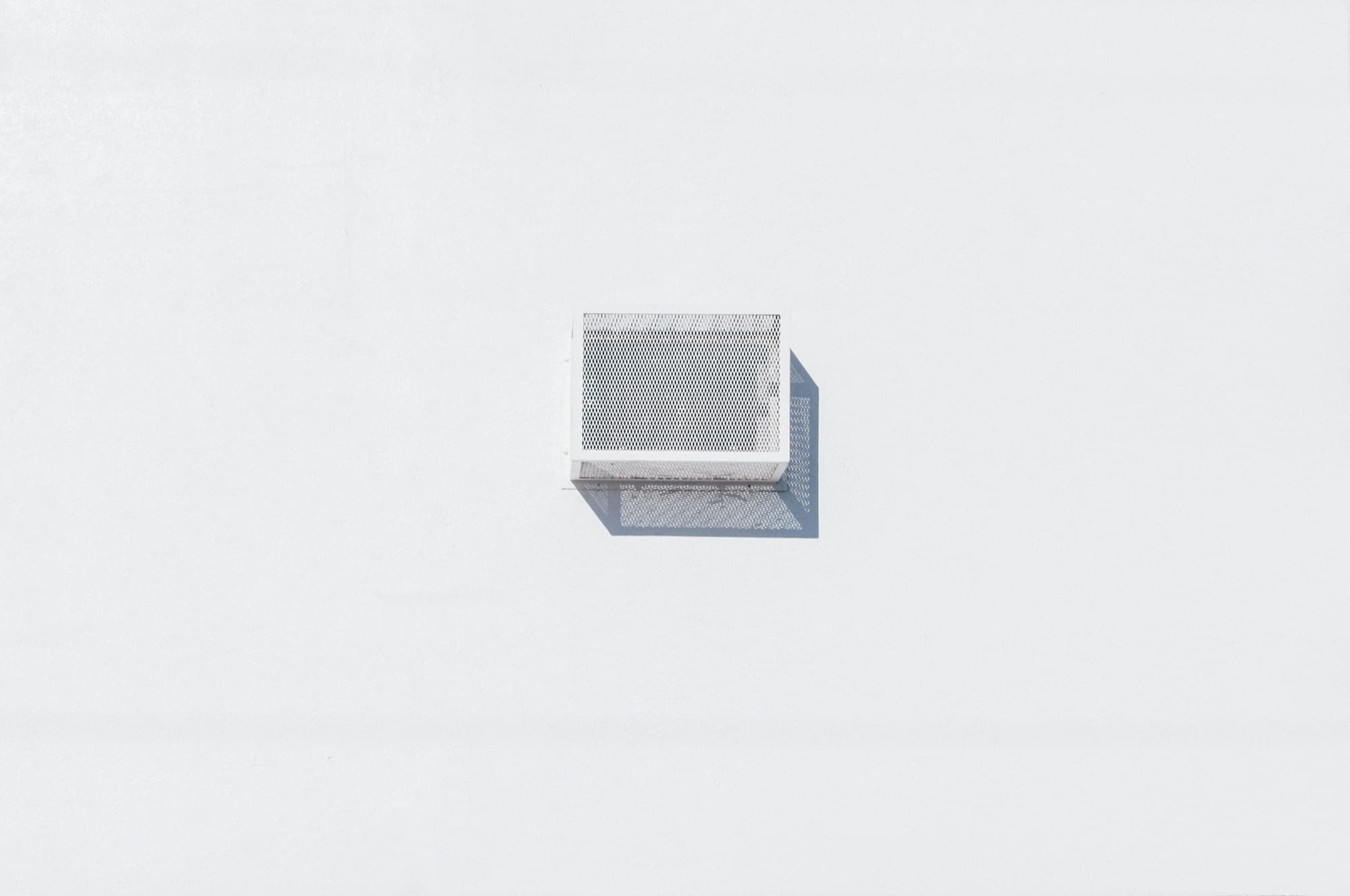 Clean wall-mounted air vent against a bright white surface