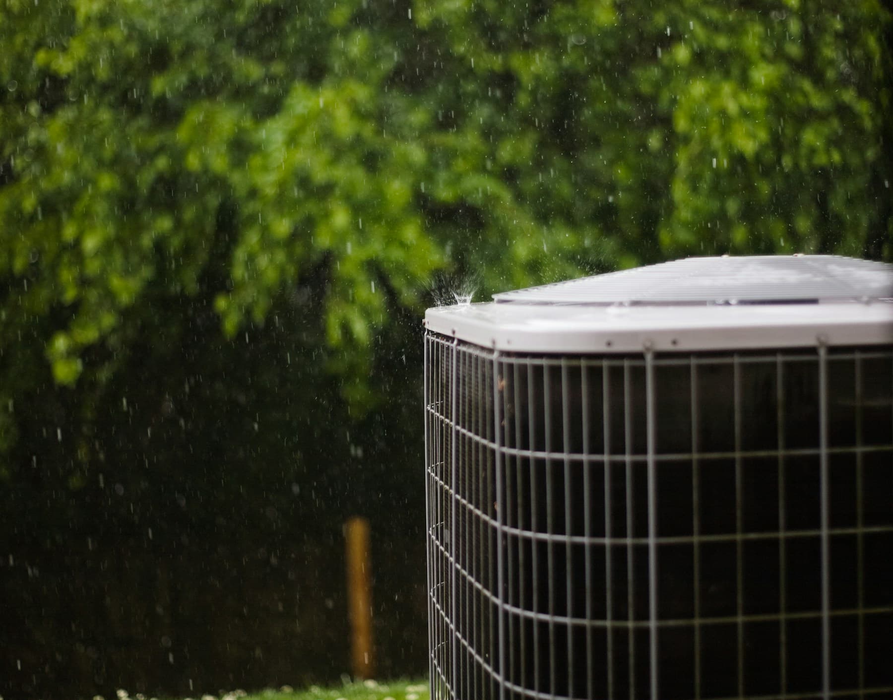 Outdoor HVAC condenser beside a home during rainfall