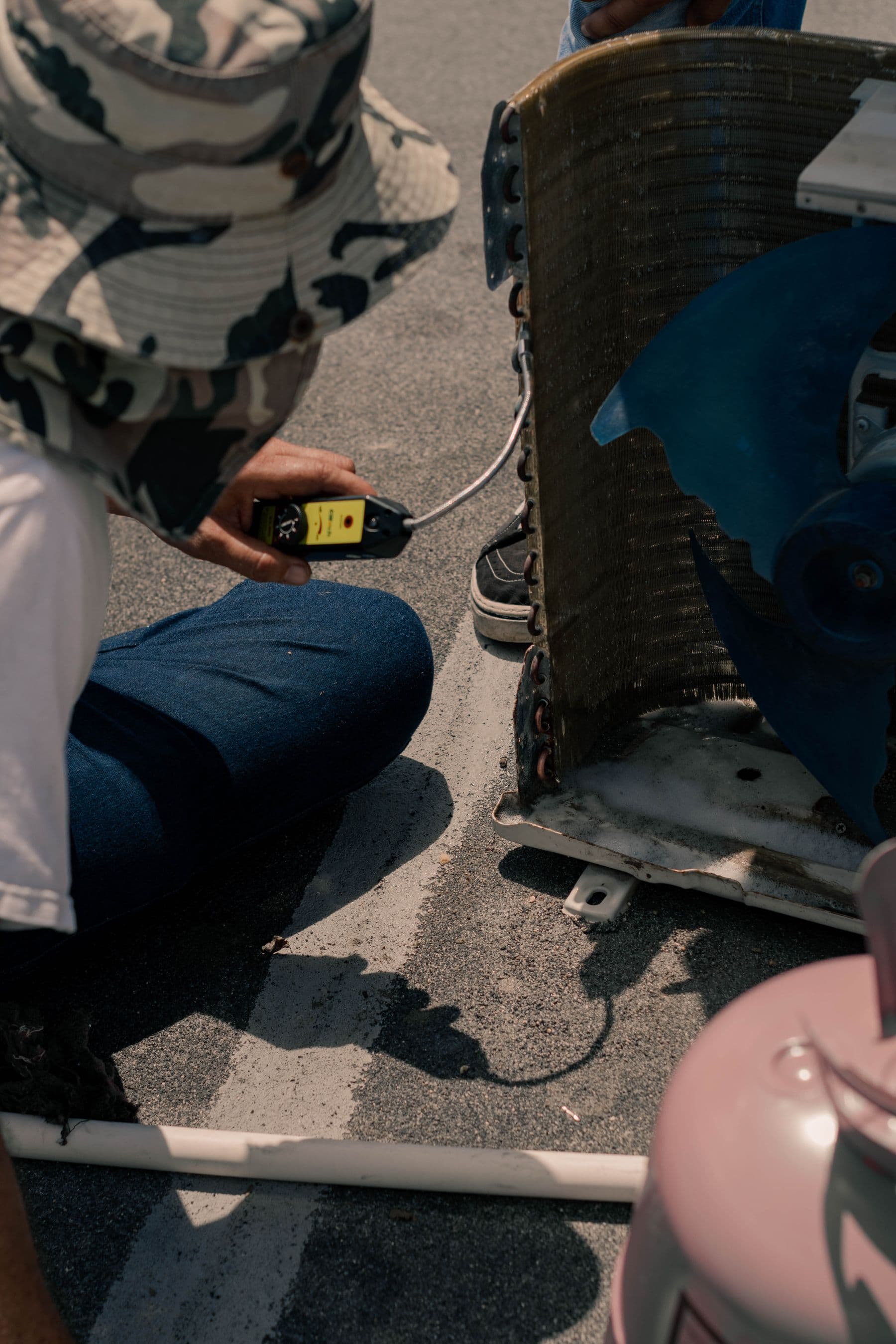 HVAC technician checking an exposed outdoor coil with a handheld probe