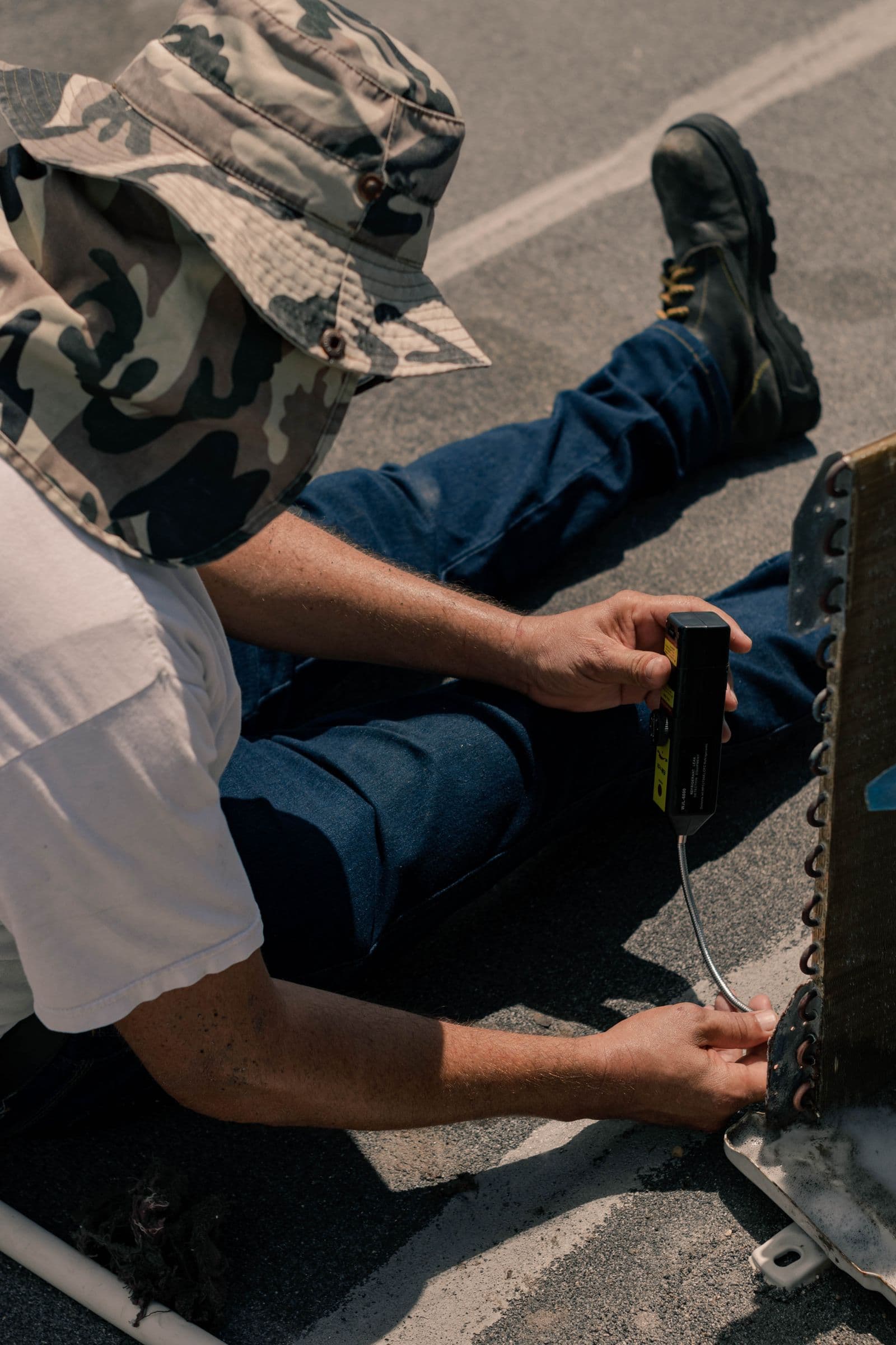 HVAC technician using a handheld diagnostic probe on outdoor equipment